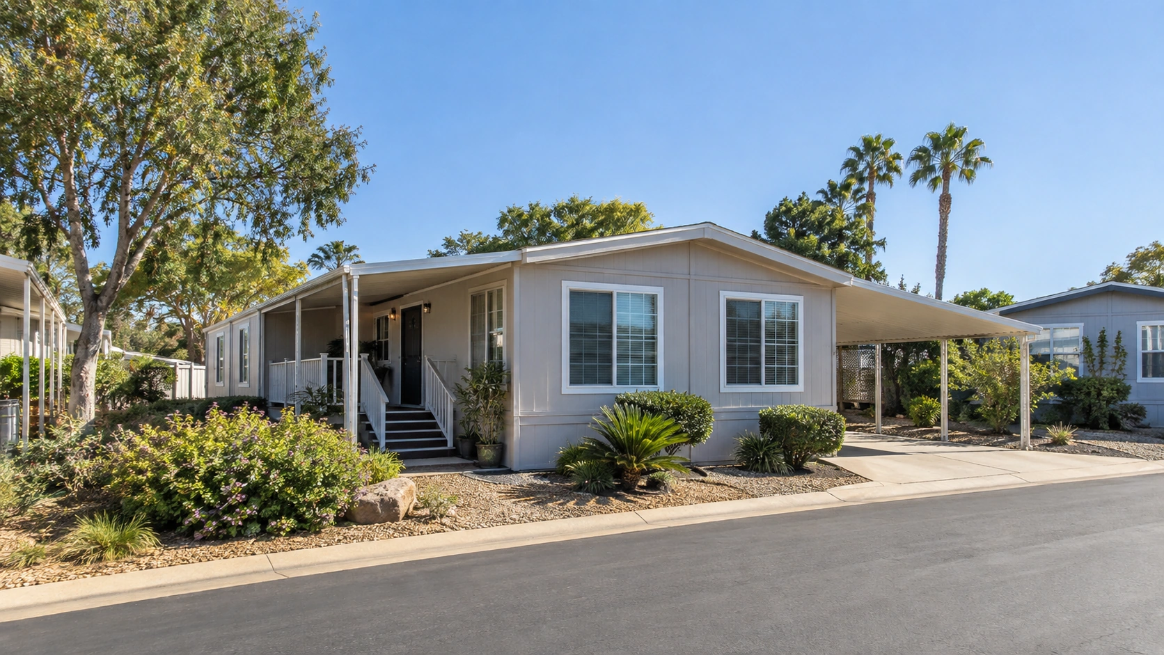 Single-story manufactured home with modest landscaping and neighboring homes in a Southern California-style community